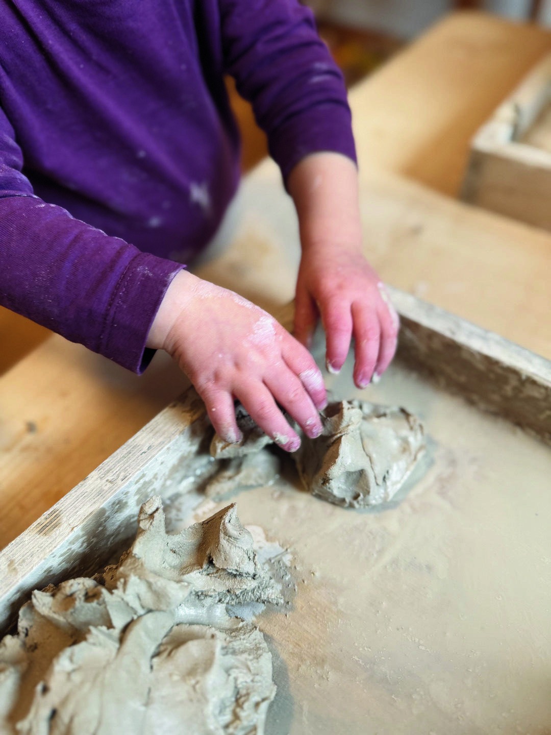 Kinderhände formen Ton auf einem Tisch